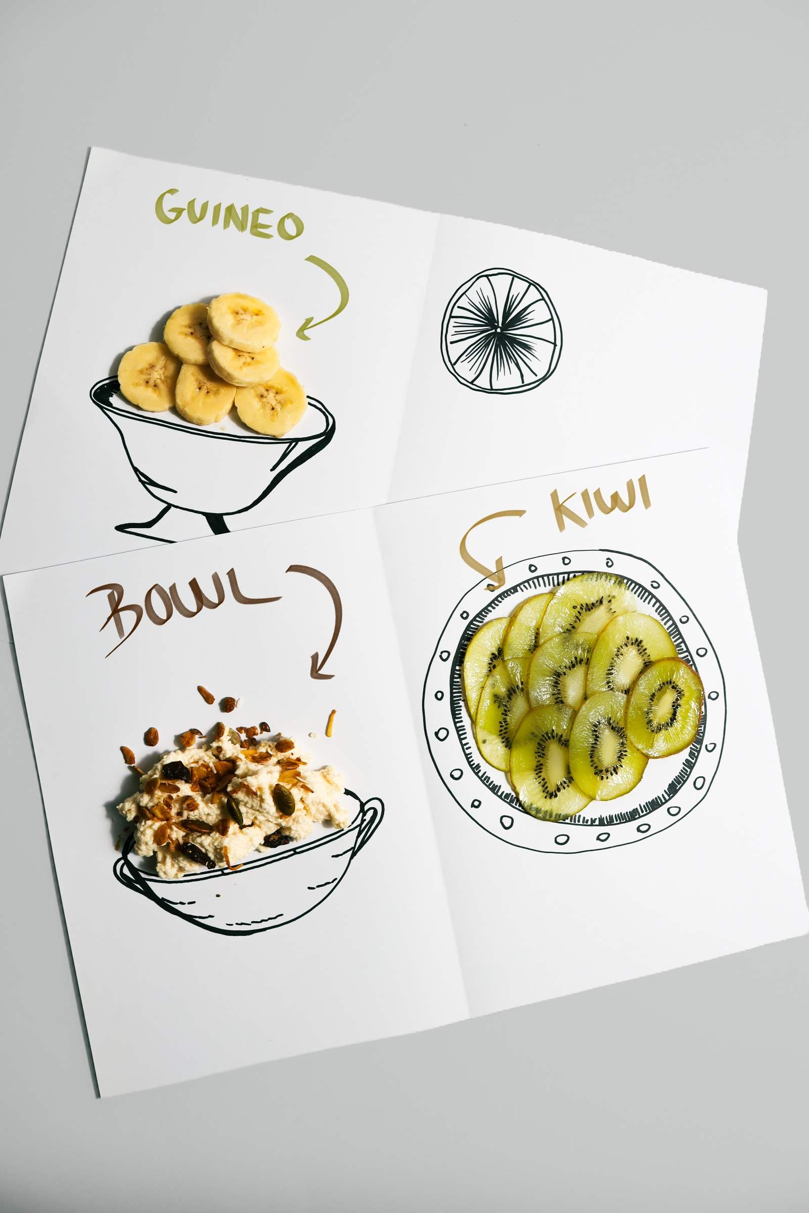 Hoja con ilustraciones de guineo, kiwi y bowl junto a la fruta real