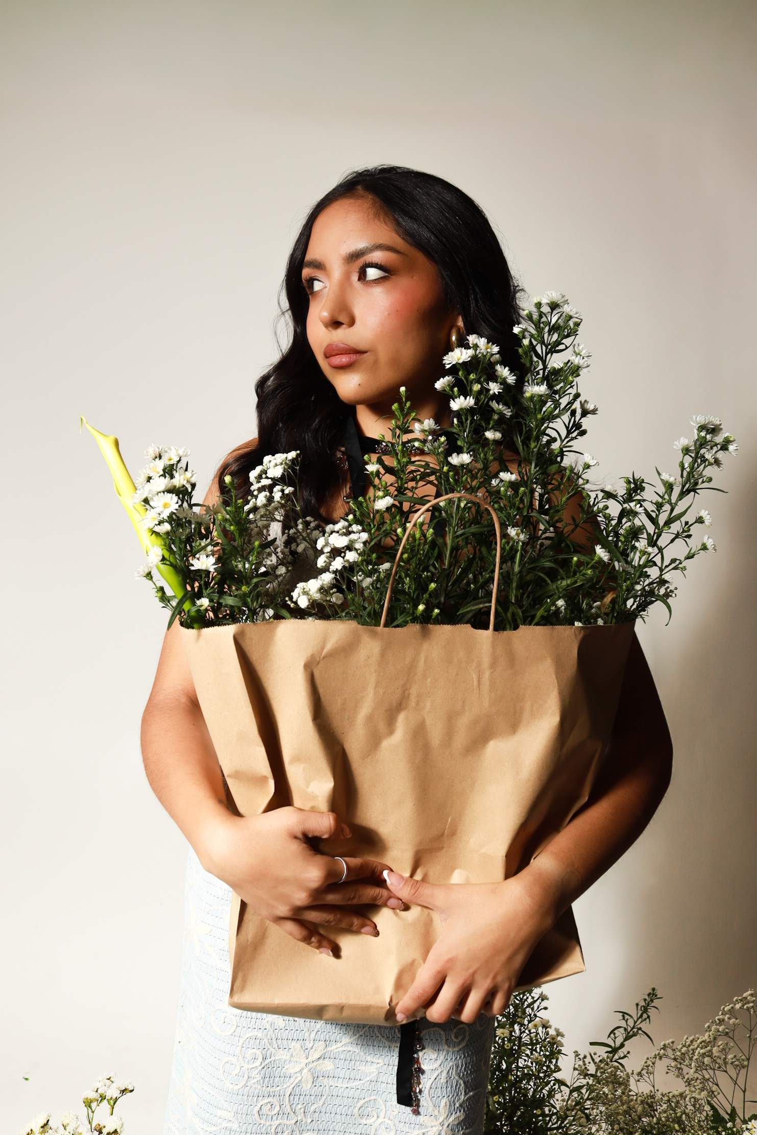 Modelo con una bolsa de papel llena de flores, mirando a un lado
